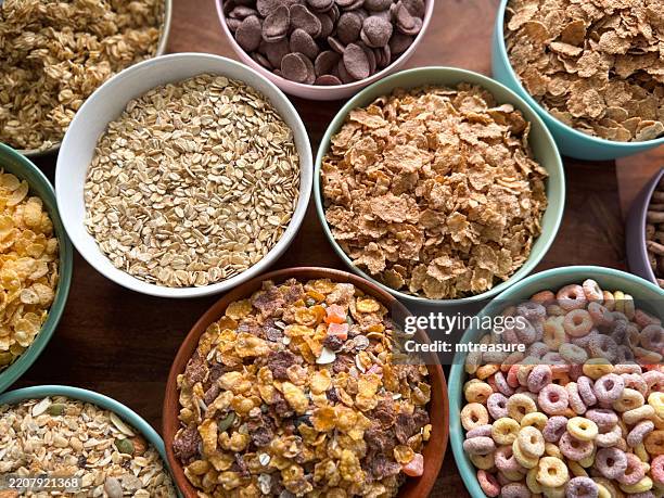 immagine full frame di ciotole di cereali sani per la colazione, fiocchi di crusca, muesli, porridge d'avena, gusci di grano croccanti al gusto di cioccolato, forme a o aromatizzate alla frutta, fiocchi di mais e muesli, vista dall'alto - cereali da colazione foto e immagini stock