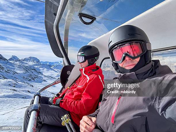 son and father skiers posing on chairlift at zermatt, switzerland - leisure equipment stock pictures, royalty-free photos & images