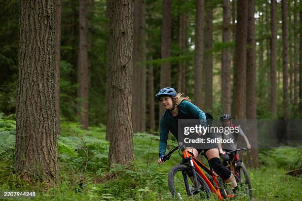 two girls tackling mountain biking trails - adrenaline chemical stock pictures, royalty-free photos & images