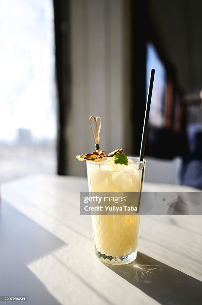 Refreshing pineapple cocktail garnished with mint and gold leaf in sunlight