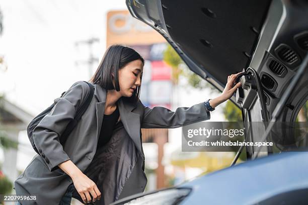 a woman putting shopping bags in the trunk of her ev car - car trunk closed stock pictures, royalty-free photos & images