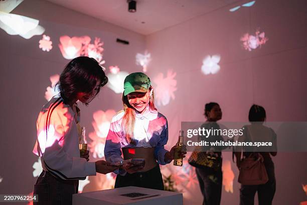 una mujer de la generación z usa su teléfono inteligente para escanear un código qr en la exposición de arte - exposición fotografías e imágenes de stock