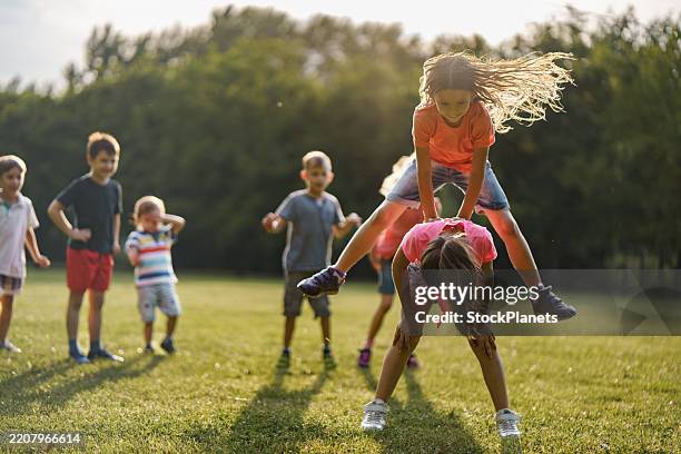 children playing leapfrog game outdoors - spelen stockfoto's en -beelden