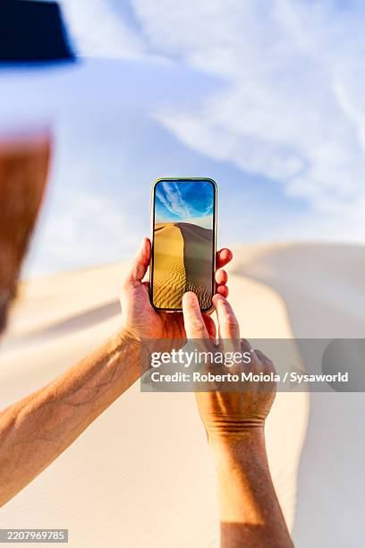 personal perspective of man photographing sand dunes - genomen met mobiel apparaat stockfoto's en -beelden
