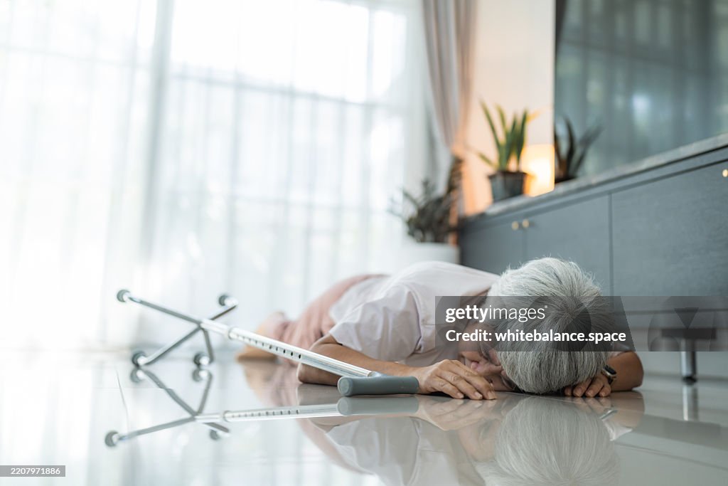 Mulher sênior caindo no chão enquanto sua bengala escorrega de seu aperto