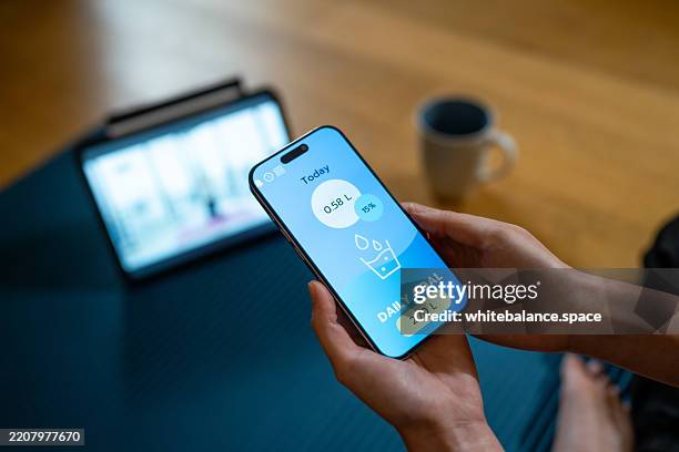 close-up shot of woman tracking her water intake on her smartphone while sipping from her glass to reach goal - data intake stock pictures, royalty-free photos & images