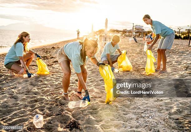 group of people cleaning beach area - initiative stock pictures, royalty-free photos & images
