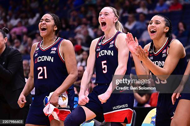 Sarah Strong, Paige Bueckers, and Azzi Fudd of the UConn Huskies react on the bench against the UCLA Bruins during the NCAA Women's Basketball...