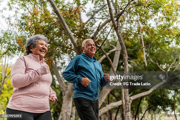 senior couple talking and running on public park - relaxation exercise stock pictures, royalty-free photos & images