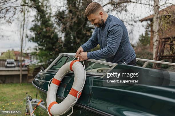 man securing a lifebuoy on a boat - buoy stock pictures, royalty-free photos & images