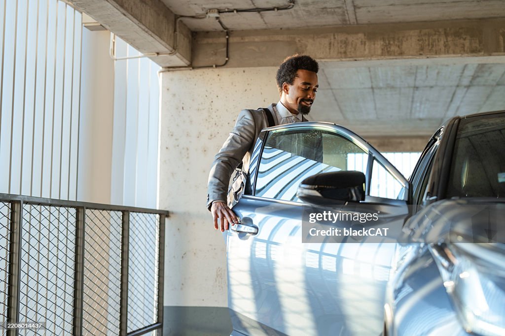 Well-dressed businessman entering his car in a modern parking structure