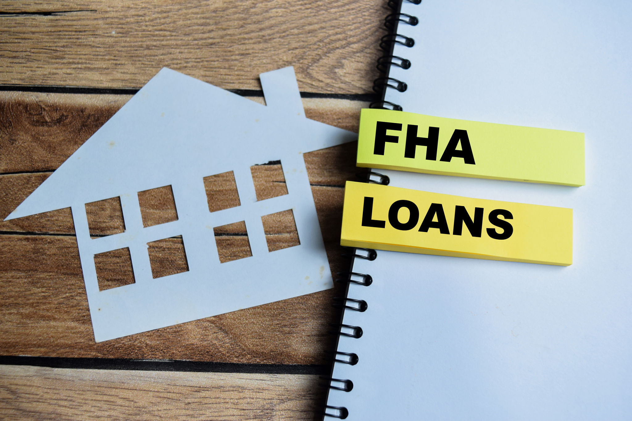 Concept of FHA Loans write on sticky notes isolated on Wooden Table. Concept of FHA Loans write on sticky notes isolated on Wooden Table.