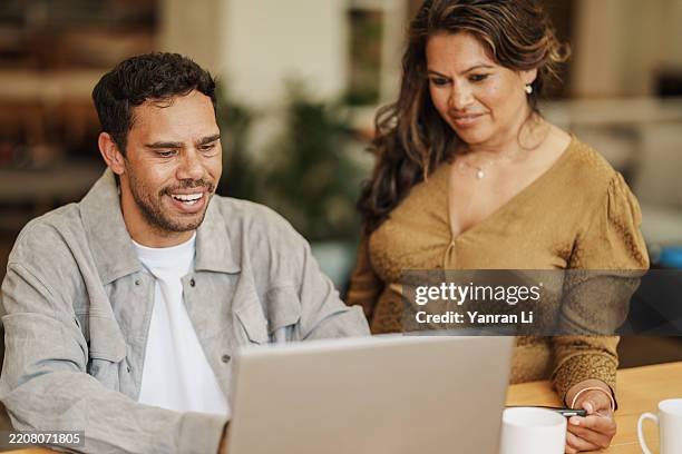 close-up of aboriginal man and multiracial woman working together in front of a laptop - minority groups stock pictures, royalty-free photos & images
