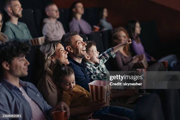 cheerful family watching a funny movie in full theatre. - nightlife stock pictures, royalty-free photos & images