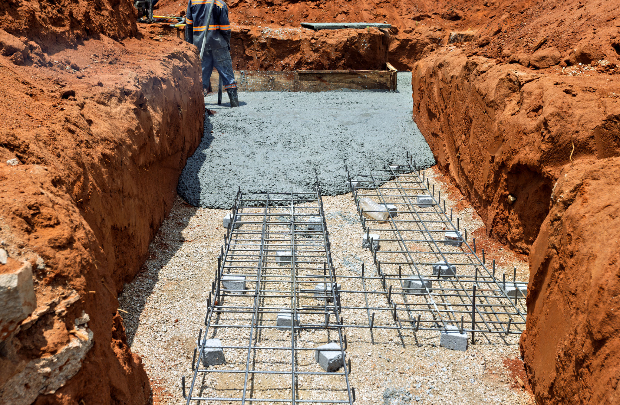 construction worker pouring concrete in footing trench reinforced concrete foundation, reinforcement steel, construction worker pouring concrete in footing trench reinforced concrete foundation, reinforcement steel,