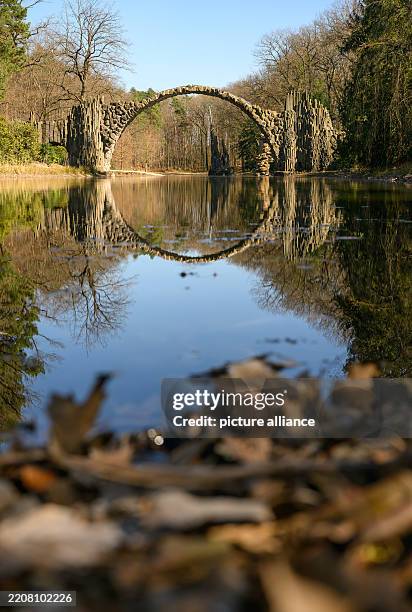 April 2025, Saxony, Kromlau: The Rakotzbrücke is reflected in a lake in the azalea and rhododendron park. Photo: Robert Michael/dpa