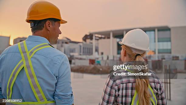 trabajadores de la construcción supervisando el sitio al atardecer con equipo de seguridad - scada fotografías e imágenes de stock
