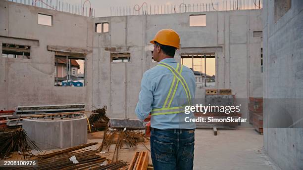 trabajador de la construcción masculino con chaleco reflectante observando el sitio de desarrollo al atardecer - scada fotografías e imágenes de stock