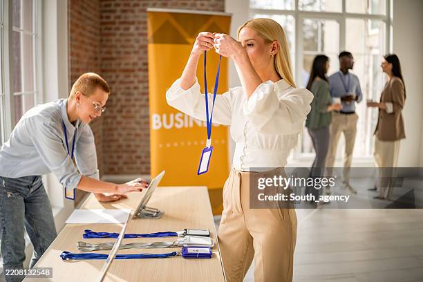 business conference participants prepare for networking and learning at a vibrant event inside a convention center - lanyard stock pictures, royalty-free photos & images
