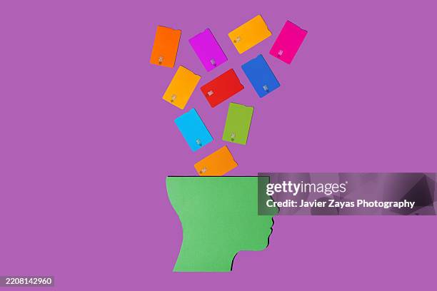 colorful credit cards falling into a green head silhouette - credit card art stock pictures, royalty-free photos & images