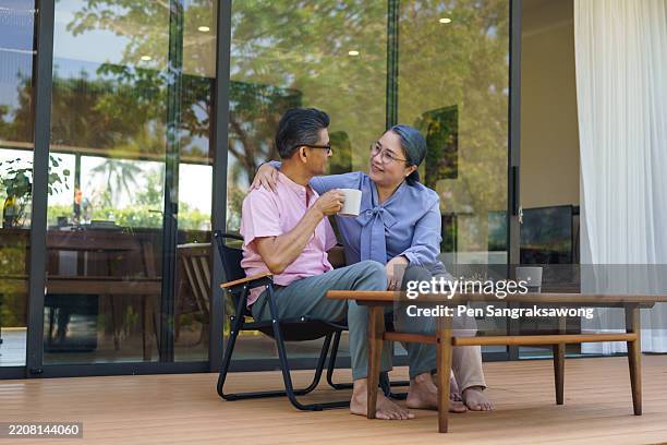 a cheerful retired elderly couple is drinking coffee and chatting on their front porch. - old lady drinking tea on porch stock pictures, royalty-free photos & images