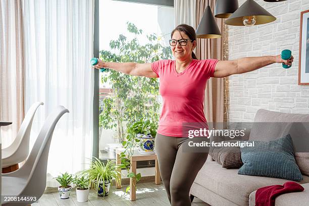 femme mature en surpoids faisant de l’exercice avec des haltères pour ses muscles des bras. femme musclée s’entraînant avec des haltères - body building photos et images de collection