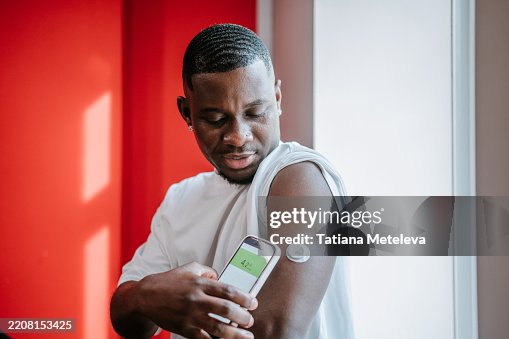African American man using glucose monitor with smartphone app. Checking glucose level with diabetes wearable sensor African American man using glucose monitor with smartphone app. Checking glucose level with diabetes wearable sensor