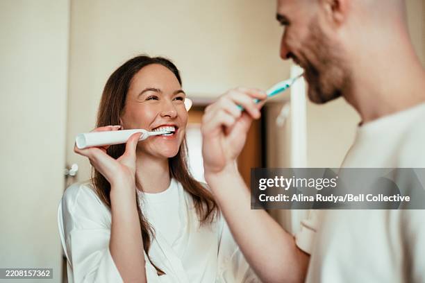 couple brushing teeth in the bathroom - lavarsi i denti foto e immagini stock