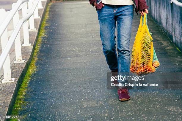 man walking home carrying groceries in a reusable shopping bag - pedestrian zone stock pictures, royalty-free photos & images