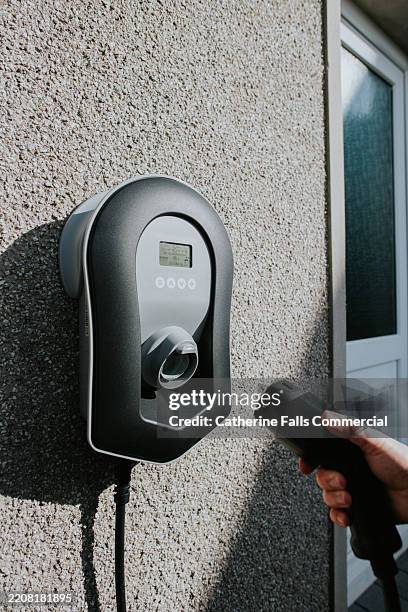 an ev charger for an electric car mounted on an exterior wall - kabelloses-laden-von-gerät-zu-gerät stock-fotos und bilder