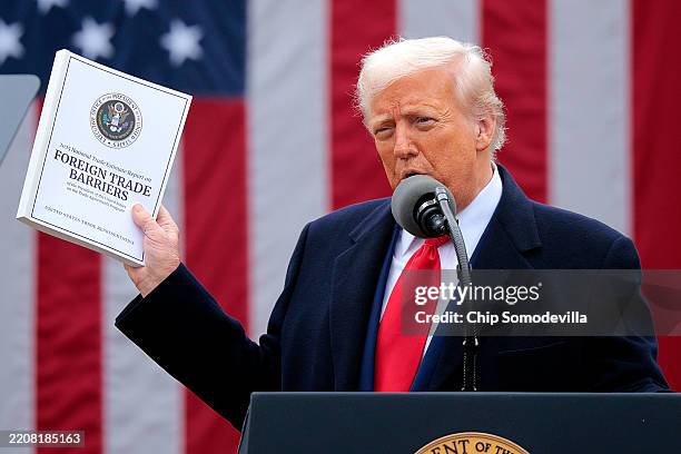 President Donald Trump holds up a copy of a 2025 National Trade Estimate Report as he speaks during a “Make America Wealthy Again” trade announcement...