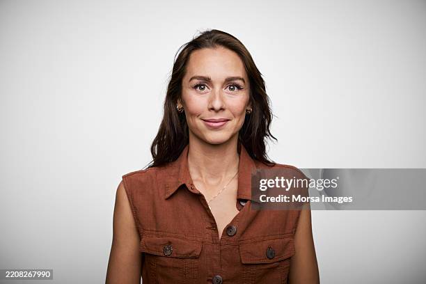 young woman with long hair poses confidently against a neutral background during a professional photoshoot - formelles portrait stock-fotos und bilder