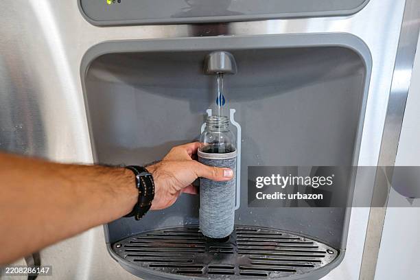 mid-adult man filling his water bottle on the water dispenser in sydney in australia - refill stock pictures, royalty-free photos & images