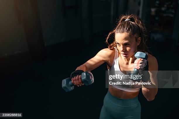 female kickboxer shadowboxing with dumbbells - woman exercise imagens e fotografias de stock