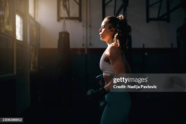 young woman working out with dumbbells - low lighting stock pictures, royalty-free photos & images