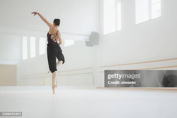 young ballet dancer performing graceful leap in sunlit white studio with ethereal atmosphere - ballet rehearsal stock pictures, royalty-free photos & images