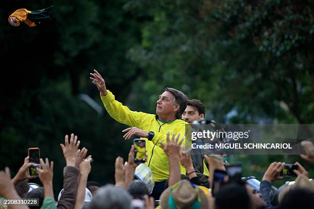 Brazil's former President Jair Bolsonaro greets supporters next to his son Renan during a rally at Paulista Avenue in Sao Paulo, Brazil, on April 6,...
