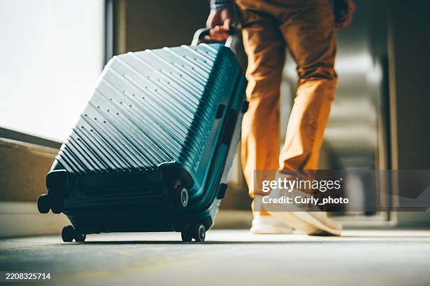 a man walks down the hotel corridor with luggage. - wheeled luggage stock pictures, royalty-free photos & images