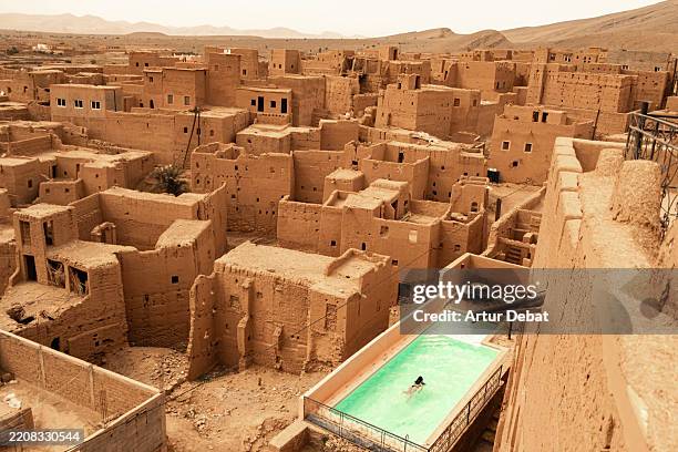 woman experience a unique travel destination swimming between desert mud village in morocco - kasbah stock pictures, royalty-free photos & images