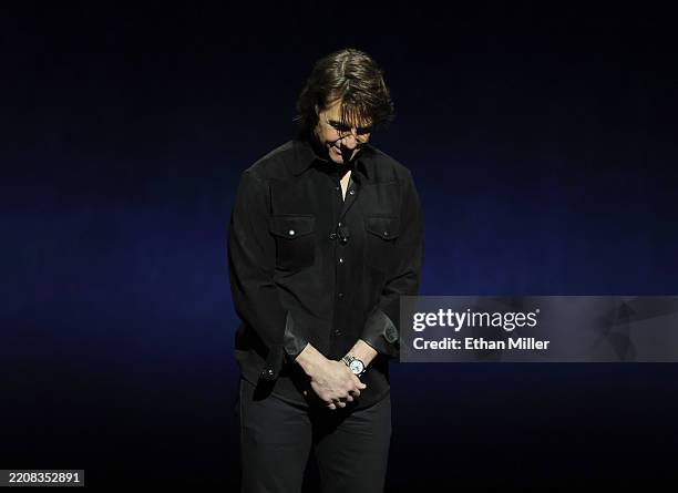 Tom Cruise bows his head onstage after asking the audience for a moment of silence for Val Kilmer, who died on Tuesday at the age of 65, at the...