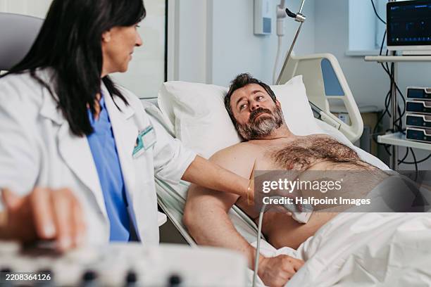 doctor performing an ultrasound on male patient's abdomen - maag darm leverziekten stockfoto's en -beelden