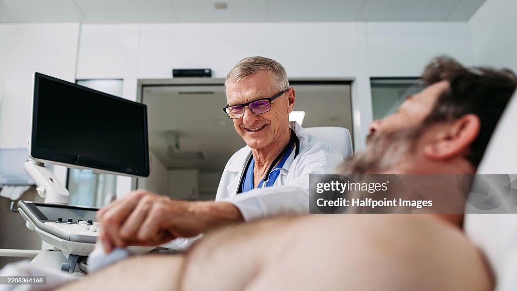 Doctor performing an ultrasound on male patient's abdomen