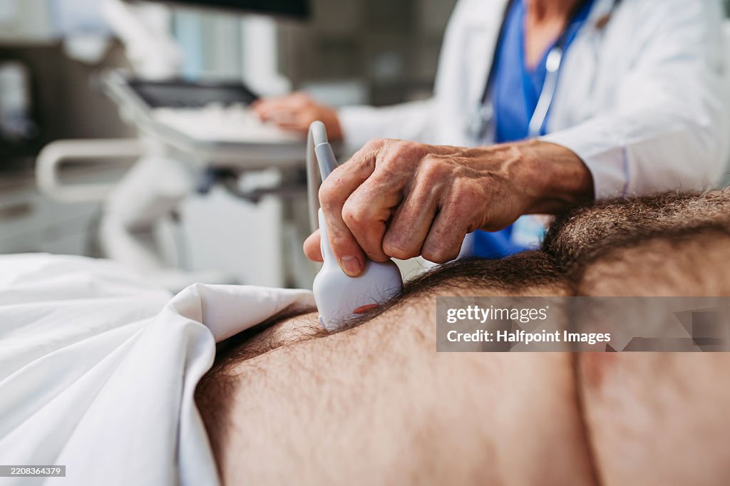 Close up of doctor performing an ultrasound on male patient's abdomen