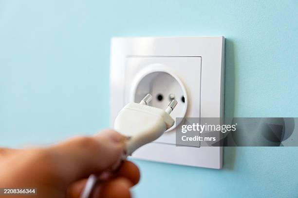 plugging cable into plug socket - prise électrique photos et images de collection