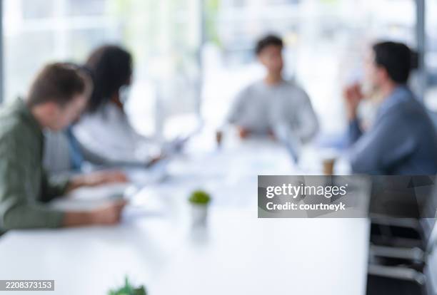 plan déconcentré d’une équipe travaillant à la table d’une salle de réunion lors d’une présentation ou d’un séminaire d’entreprise. - flouté photos et images de collection