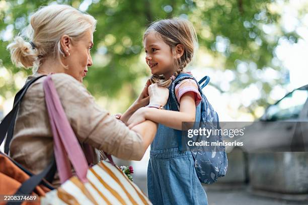 mother preparing daughter for school with a cheerful smile in morning light - skolstart bildbanksfoton och bilder