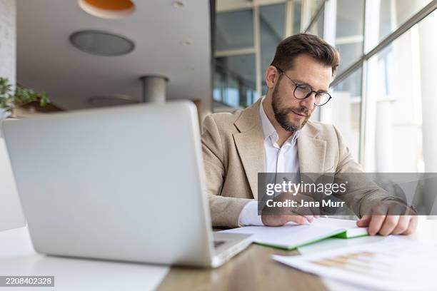 serious businessman taking notes in modern workplace - law student stock pictures, royalty-free photos & images