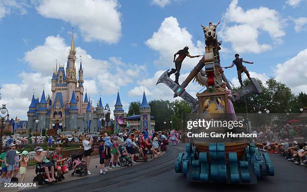 People watch as Flynn Rider and Rapunzel ride on the Tangled float during the daily Festival of Fantasy Parade at the Magic Kingdom Park at Walt...