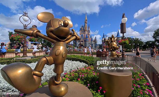 Statues of Mickey Mouse and Minnie Mouse stand in a garden in front of Cinderella's Castle at the Magic Kingdom Park at Walt Disney World on April 3...