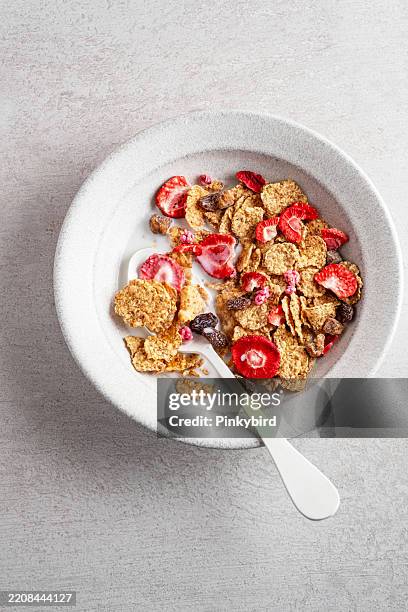 cornflakes cereal and strawberry bowl for breakfast on bowl. dried strawberries and corn flakes. healthy breakfast option: wheat flakes with dried strawberries. whole grain flakes with milk and dried berry fruits. - raisin bran stock pictures, royalty-free photos & images